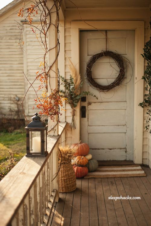 Bittersweet vine fall entryway decor with orange berries wreath pumpkins and rustic porch railing