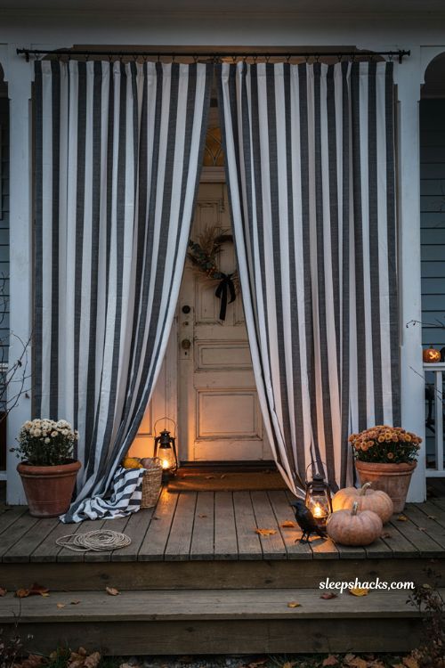 Black and white striped curtains framing a dramatic Halloween front porch entrance