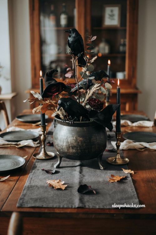 Black cauldron with dark flowers witch hats and crows for a dramatic Halloween table centerpiece