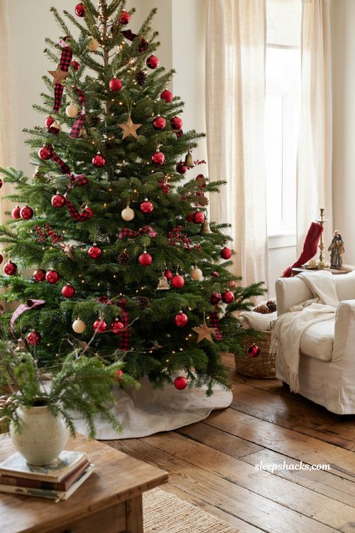 Buffalo plaid ribbon and red ornaments on a traditional Christmas tree