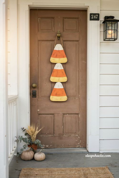 Candy corn Halloween door hanger with orange yellow and white stacked design on a front door