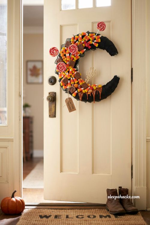 Candy corn chaos wreath with lollipops faux chocolate skeleton hand and playful Halloween candy decor
