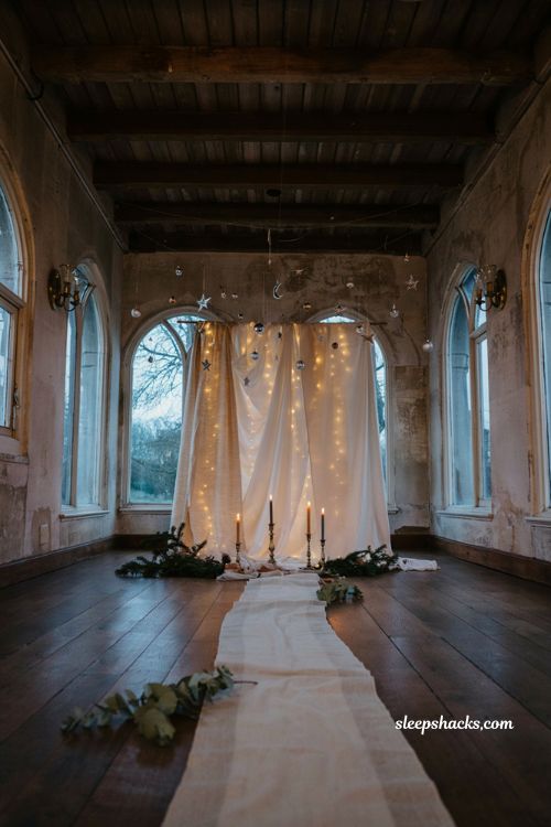 Celestial winter wedding ceremony backdrop with navy silver stars fairy lights and white fabric