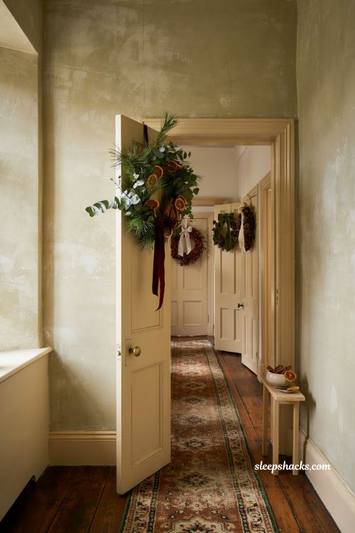 Charming interior door christmas wreaths with dried oranges cinnamon sticks and velvet ribbons in a hallway