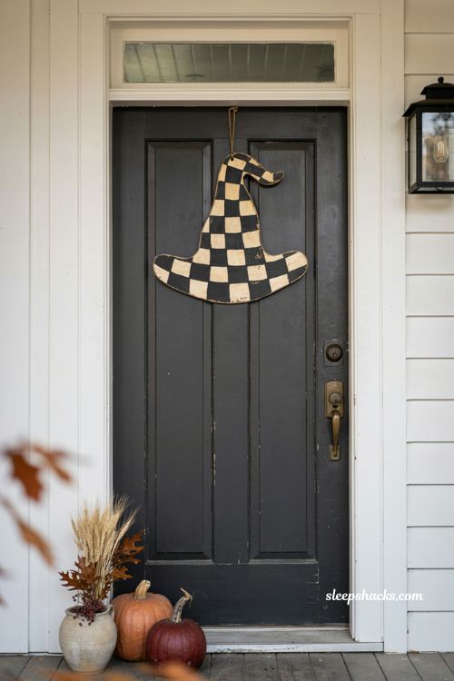 Checkered Halloween door hanger with black and cream pumpkin design on a rustic front door