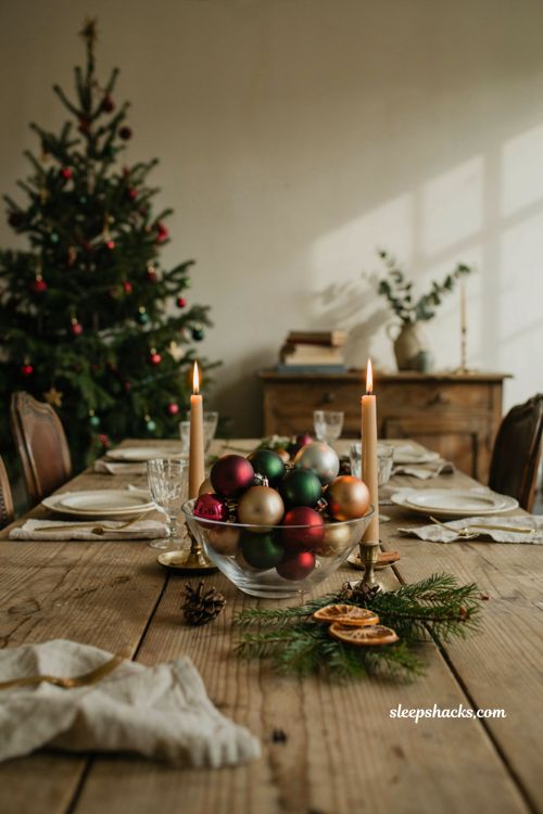 Christmas tablescape with ornament bowl centerpiece greenery and candlelight
