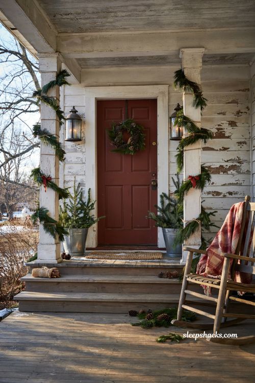 Country christmas porch with garland wrapped columns and rustic farmhouse holiday decor