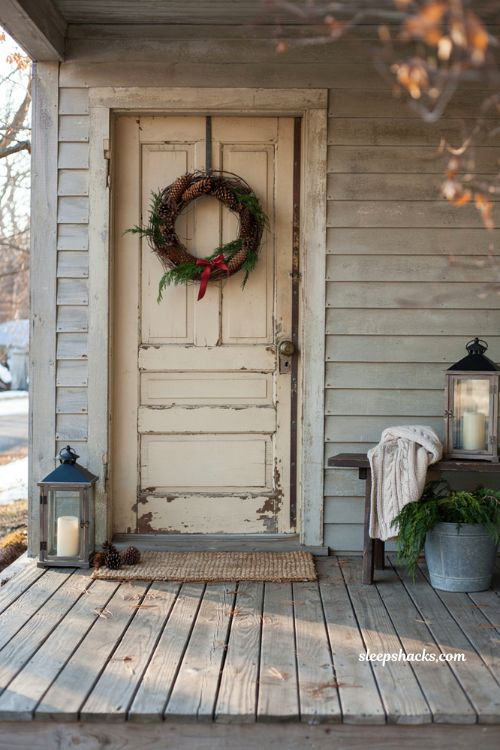 Country christmas porch with grapevine pinecone wreath and rustic farmhouse front door