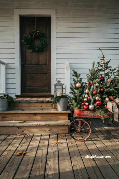 Country christmas porch with vintage red wagon filled with mini christmas trees and ornaments