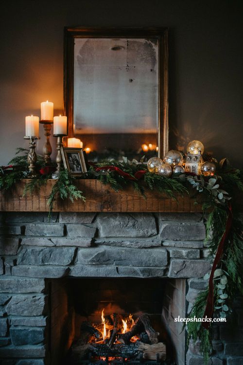 Cozy asymmetrical christmas mantel display with candles velvet ribbon and lush green garland