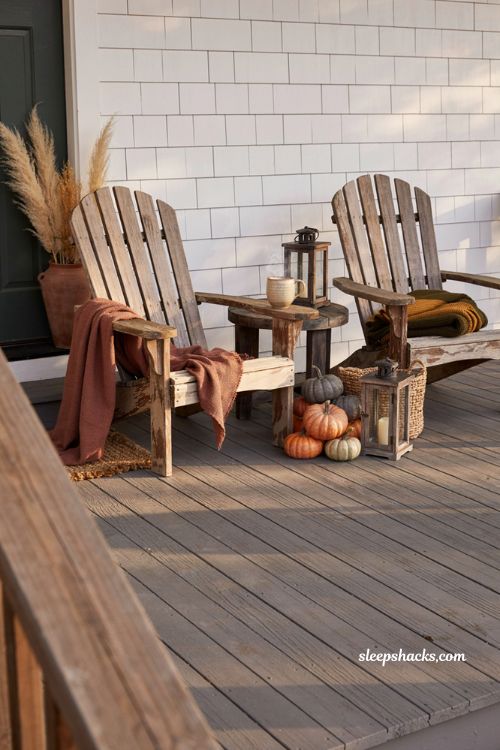 Cozy fall outdoor seating area with Adirondack chairs throw blanket lanterns and pumpkins