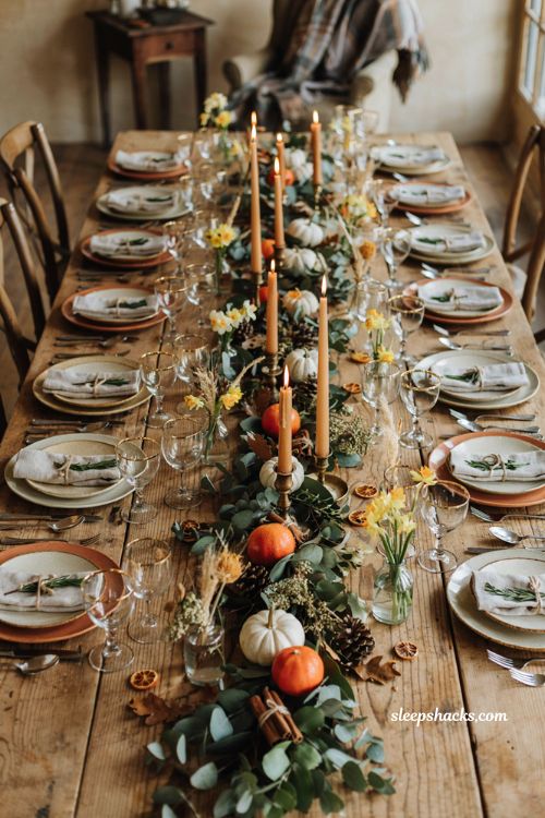 Cozy rustic fall baby shower centerpiece idea with autumn leaves orange pumpkins clementines daffodils and candles