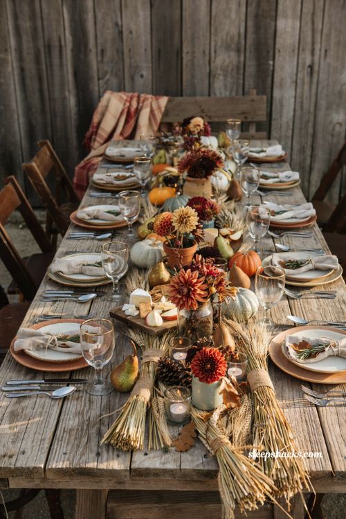 Cozy rustic harvest baby shower centerpiece with wheat stalks squash and dahlias on a barn wood table