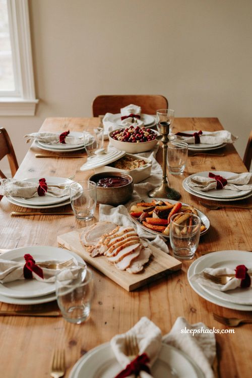 Cranberry ribbon Thanksgiving table setting with white plates velvet napkins simple serving dishes and a low bowl of cranberries 
