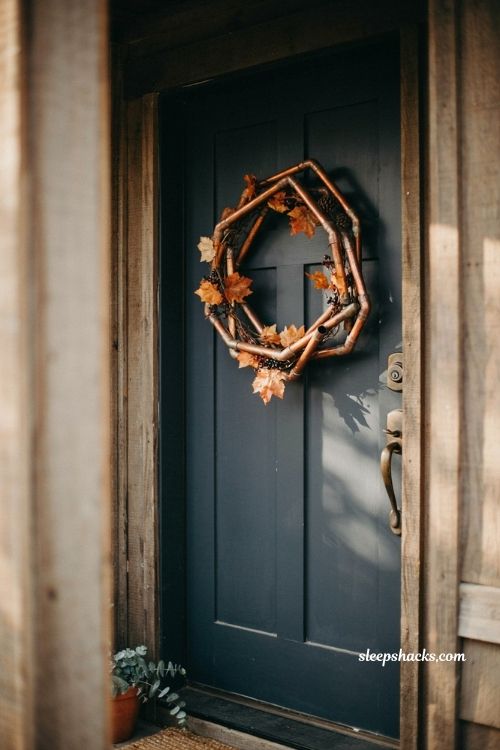DIY vintage fall wreath with antique copper pipe and autumn foliage on a black front door