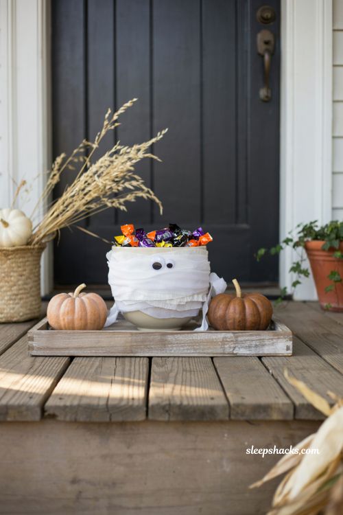 Easy Halloween mummified candy bowl with googly eyes and treats on a cozy front porch