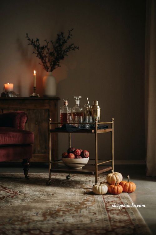Elegant Halloween bar cart decor with vintage bottles dark glassware and pumpkins