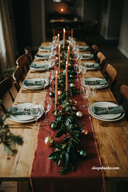 Elegant christmas tablescape with low garland burgundy runner taper candles and gold rimmed glassware