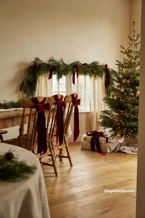 Elegant deep crimson velvet ribbon bows tied on dining chairs for festive christmas decor