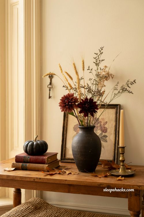 Fall Halloween decor with black vase dried wheat dark florals and cozy autumn styling