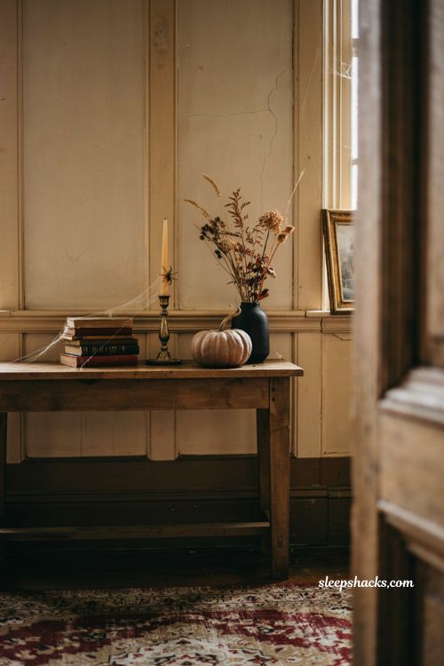 Fall Halloween entryway decor with subtle cobwebs old books and a single spider