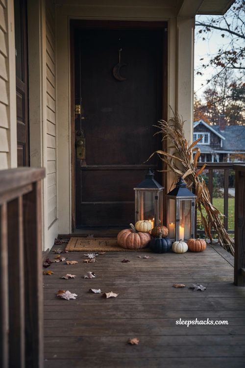 Fall Halloween porch decor with tall black lanterns pumpkins and cozy front door styling