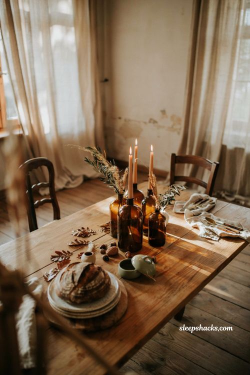 Fall centerpiece with vintage amber bottles taper candles and rustic dining table
