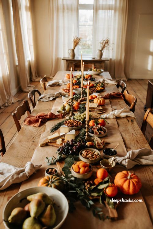 Fall charcuterie board centerpiece with seasonal fruit herbs and rustic dining table