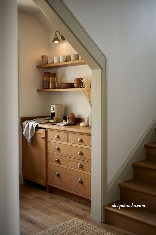 Fall coffee bar decor ideas under stairs with open shelves wood cabinetry and cozy accents 
