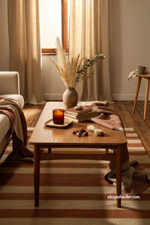 Fall coffee table decor with a loosely draped rust knit throw warm wood and cozy seasonal textures 