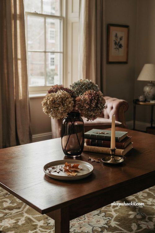 Fall coffee table decor with dried hydrangeas in a dark glass vase and vintage coffee table books 