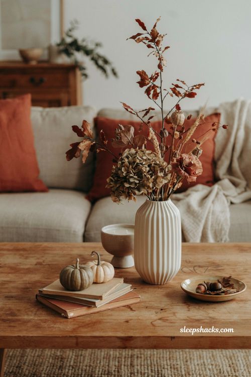 Fall coffee table decor with scented candle floral arrangement and cozy autumn accents 