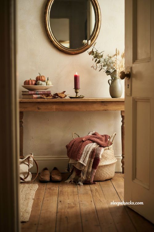 Fall entryway table decor with cozy throw blanket basket pumpkins and candles