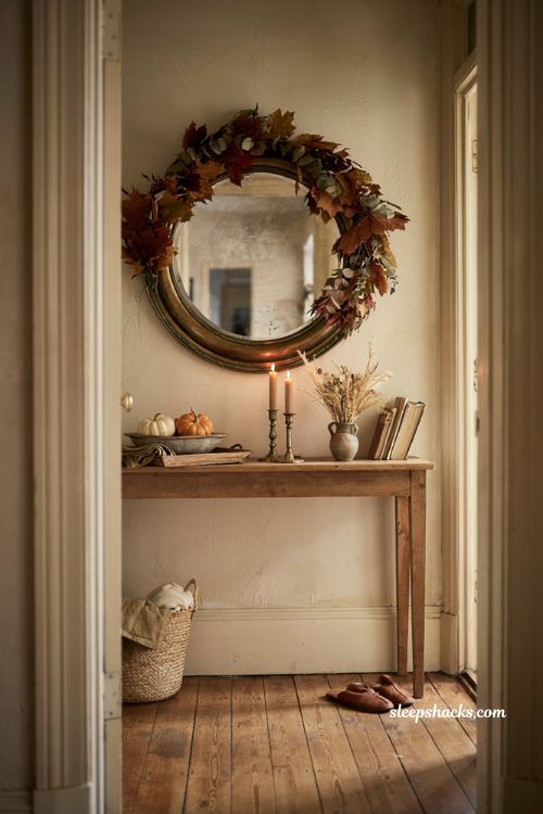 Fall entryway table decor with leaf garland around mirror pumpkins and candles