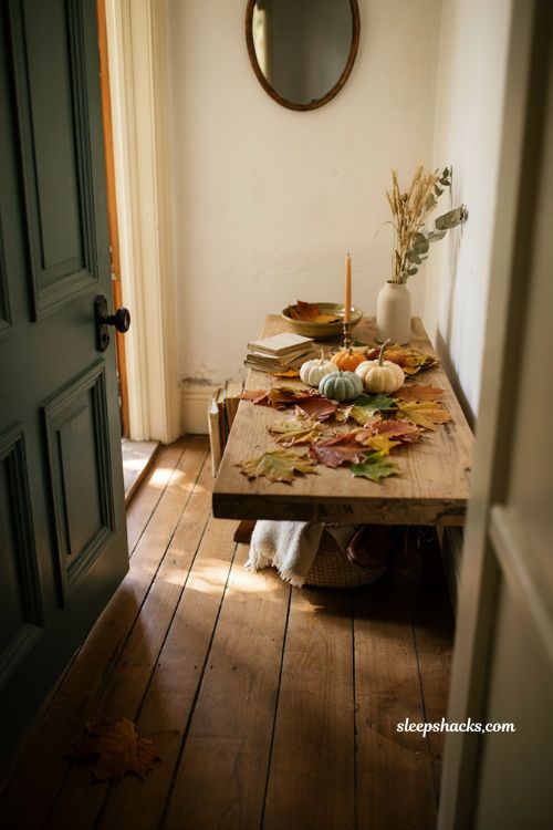 Fall entryway table decor with scattered leaves mini pumpkins and dried stems