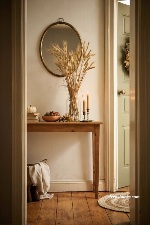 Fall entryway table decor with wheat stalks in glass vase pumpkins and books