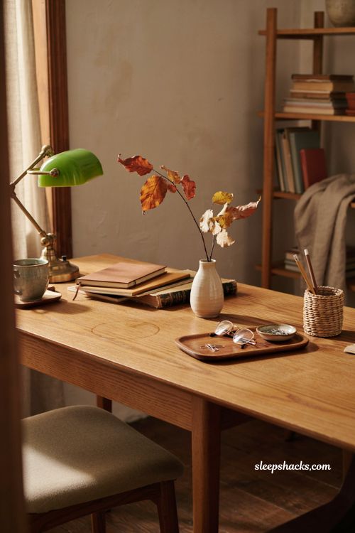 Fall office decor with a vase of autumn leaves on a cozy workspace desk