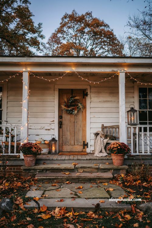 Fall porch decor with warm white string lights pumpkins wreath and cozy evening glow