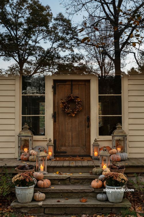 Fall porch lantern decor with pumpkins and warm evening glow by the front door