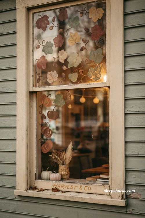 Fall window painting ideas with hand painted leaves pumpkins and cozy autumn storefront decor