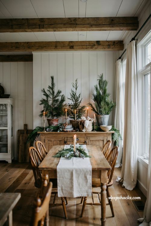 Farmhouse christmas dining room buffet decorated with layered evergreen garland and frosted trees