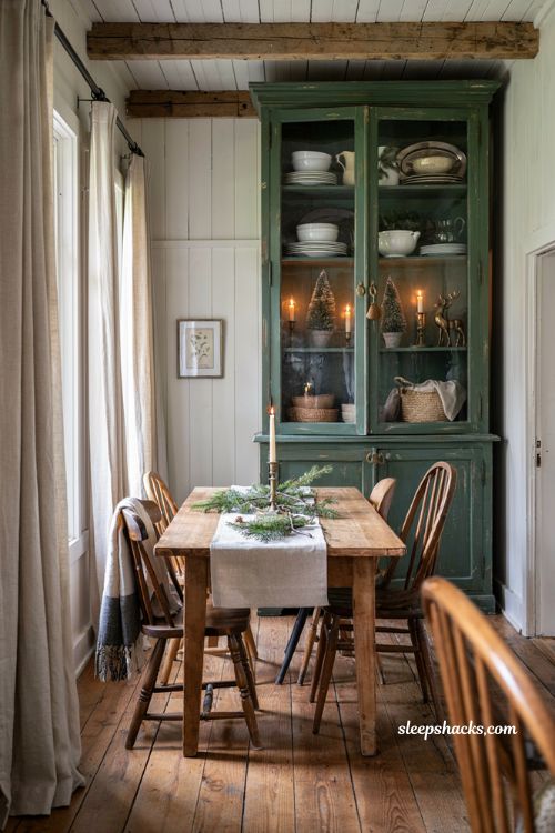 Farmhouse christmas dining room hutch styled with layered greenery and vintage white dishware