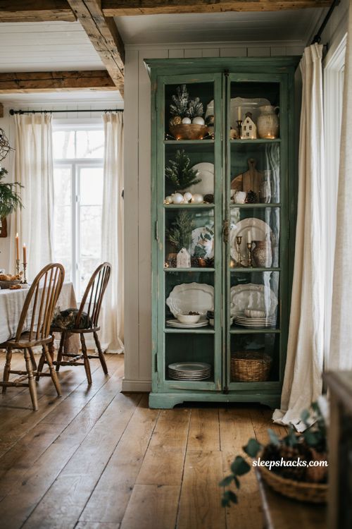 Farmhouse christmas hutch styled with vintage white dishware and fresh holiday greenery