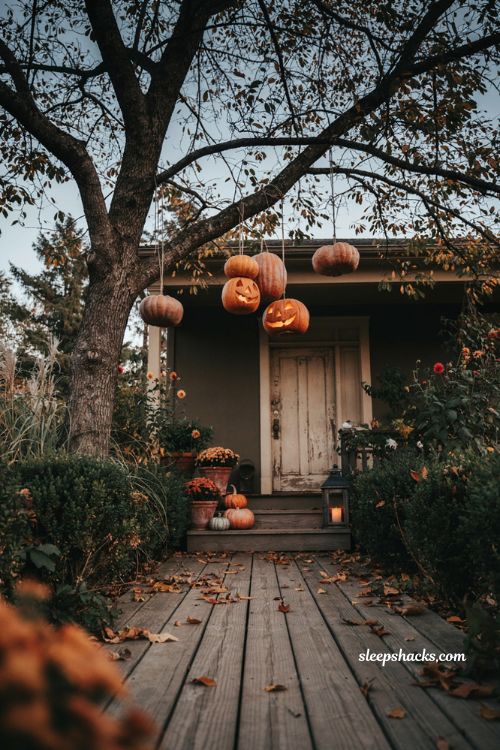 Floating pumpkins and glowing jack o lanterns hanging from tree branches for eerie Halloween porch decor