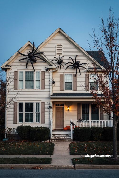 Giant spider Halloween house decorations crawling across light siding