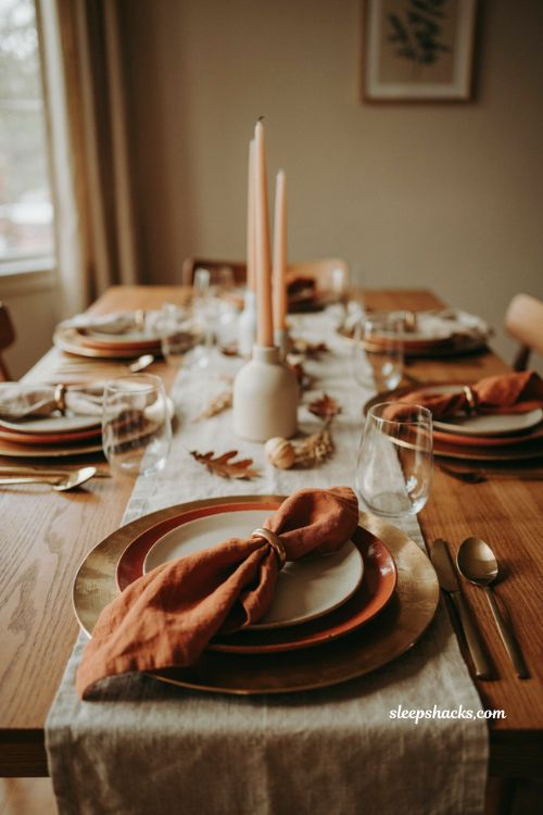 Gold charger Thanksgiving table setting with rust plates bow shaped linen napkins gold rings and warm autumn decor 