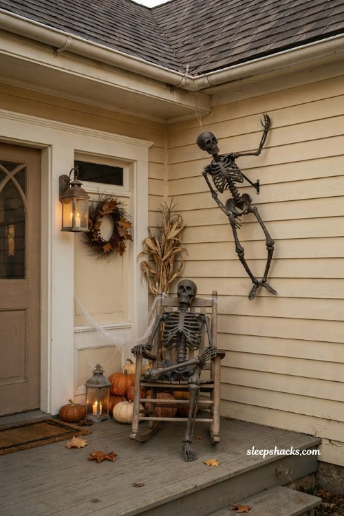 Halloween front porch with climbing skeletons on house siding and a relaxed skeleton on a porch chair, cozy autumn cottage decor, vintage pumpkins and lanterns, playful spooky porch decorating idea, warm seasonal home exterior, photorealistic editorial photography