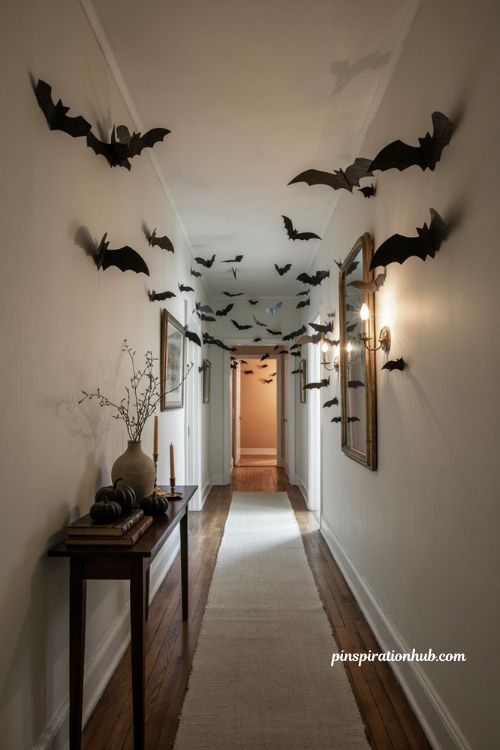 Halloween hallway ideas with flying bats on white walls vintage mirror and spooky decor