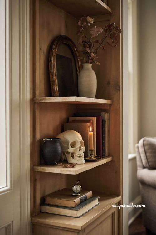 Halloween living room shelf with a matte skull styled between vintage books and antique decor 