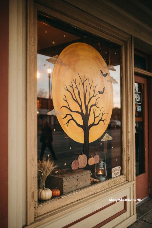 Harvest moon fall window painting with golden moon tree pumpkins and cozy autumn storefront decor